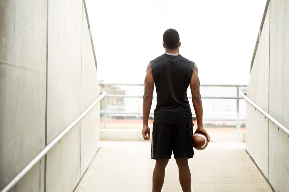 College athlete standing in stadium with football